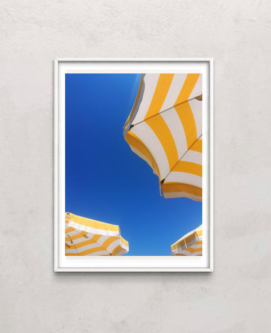 Bottom view of a yellow and white sunbrella on the beach or near a pool