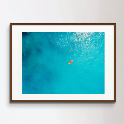 Aerial view of woman on stand up paddle board in blue ocean.