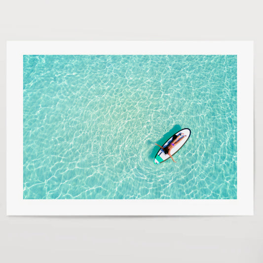 Aerial view of a woman on a surfboard in the turquoise waters