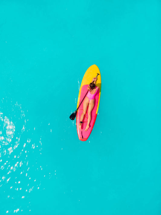 Beautiful woman on stand up paddle board in blue ocean